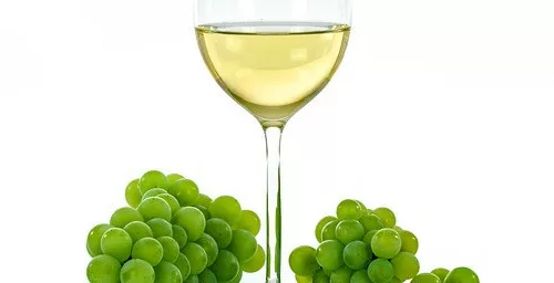 a glass of white wine with white grapes