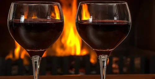 Two glasses of wine in front of a chimney