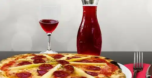 bottle of red wine with a glass of red wine and a pizza