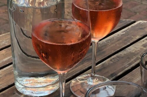 Grenache Noir Grape In Provence - two glasses of rosé with a bottle of water on a wooden table